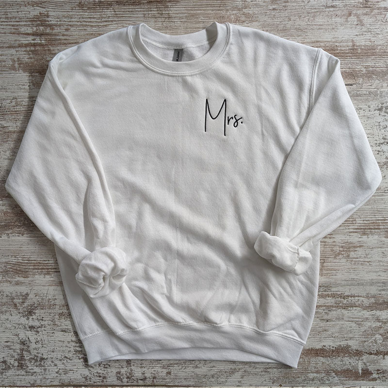 White crewneck sweatshirt with black script Mrs. embroidered on the chest